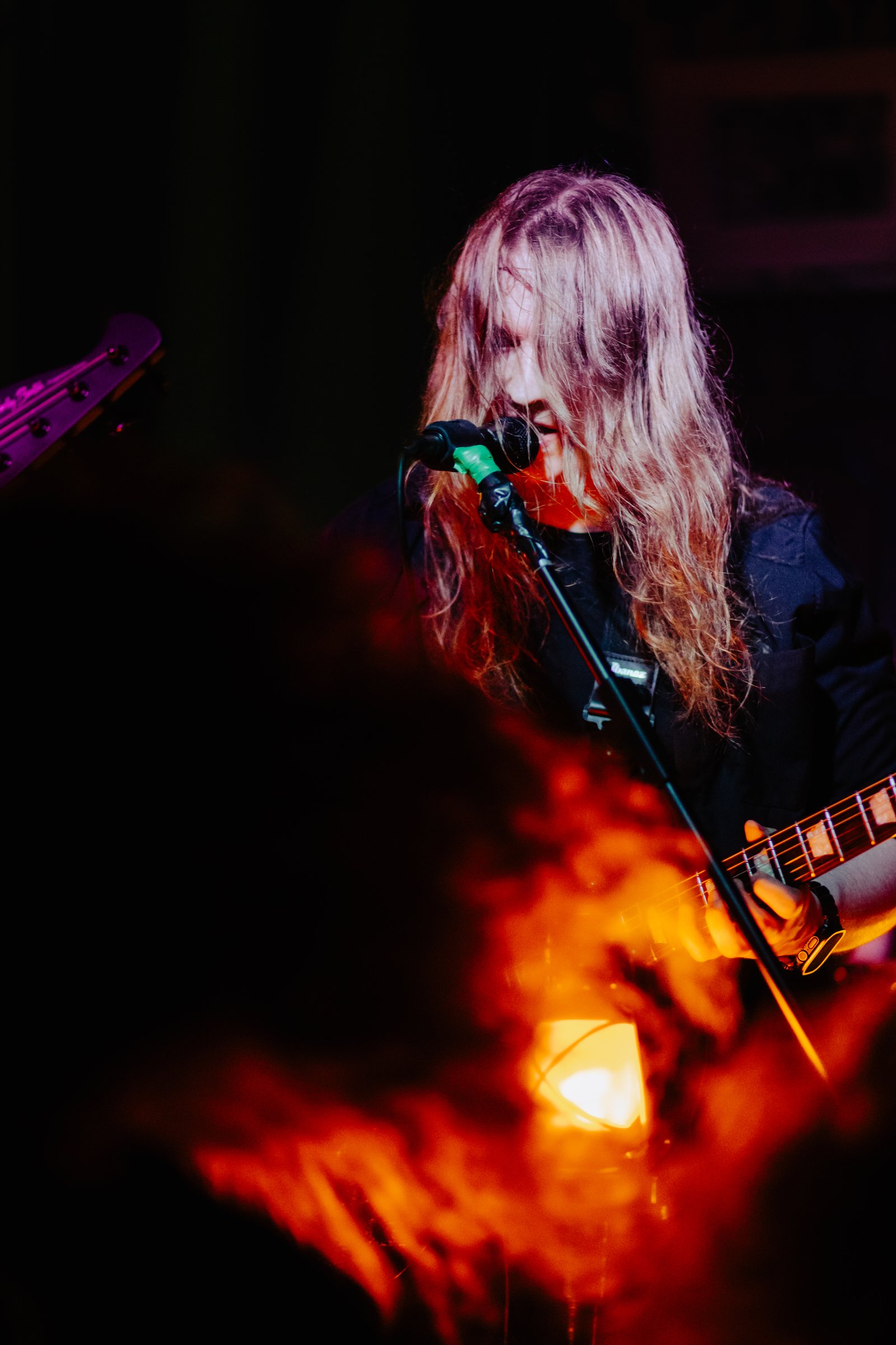 Krystian Jurkiewicz singing in orange stage light in Olsztyn